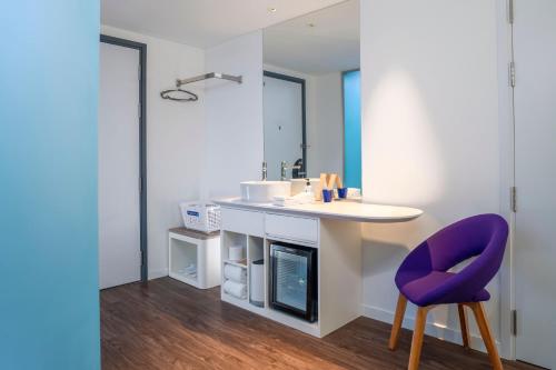 a bathroom with a sink and a purple chair at Tru by Hilton Can Tho Cai Khe in Can Tho