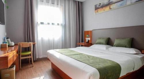 a bedroom with a large bed and a desk and a window at Vatica Shanghai Jiading District Anting Metro Station Moyu Road Hotel in Shanghai