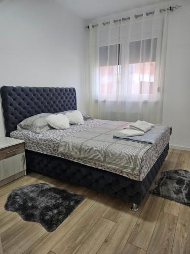 Una cama en un dormitorio con dos alfombras. en Miss LuX, en Mladenovac