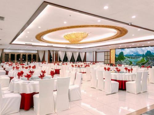 a large banquet hall with white tables and white chairs at Yangshuo Greenlotus Hotel in Yangshuo