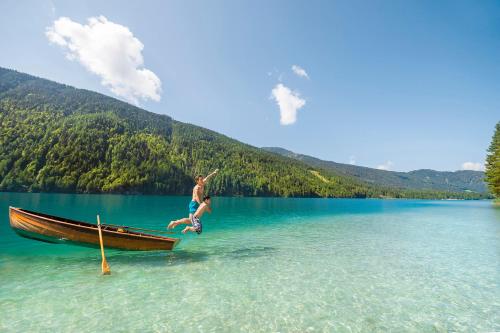 a boy jumping off of a boat in a lake at Pension Bergblick - Nebenhaus C in Neusach
