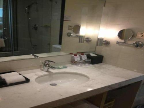 a bathroom counter with a sink and a mirror at Ramada Plaza Shenyang Citycenter in Shenyang