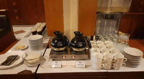 a table with cups and coffee makers on a table at Alexander Hotel Tegal in Tegal