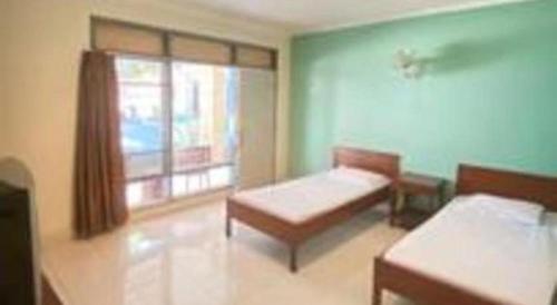 a room with two beds and a window at Alexander Hotel Tegal in Tegal