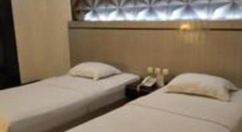 two twin beds in a room with a window at Alexander Hotel Tegal in Tegal