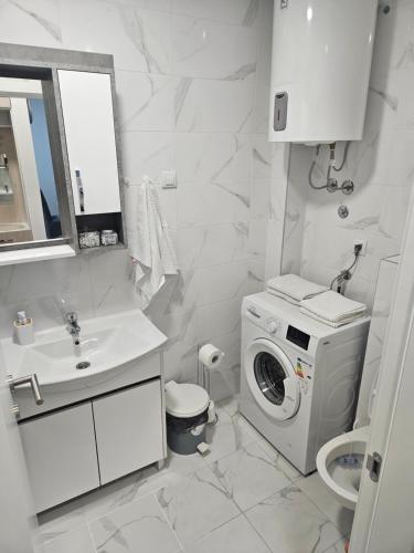 baño blanco con lavadora y lavamanos en Miss LuX, en Mladenovac
