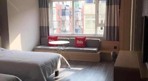 a bedroom with a bed and a window with red pillows at ibis Shenyang north station in Shenyang