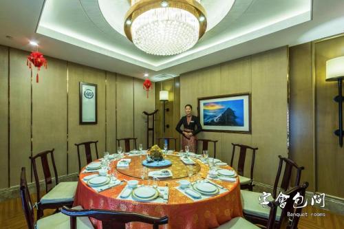 a man standing in front of a table in a room at Huangshan Yupinglou Hotel in Huangshan
