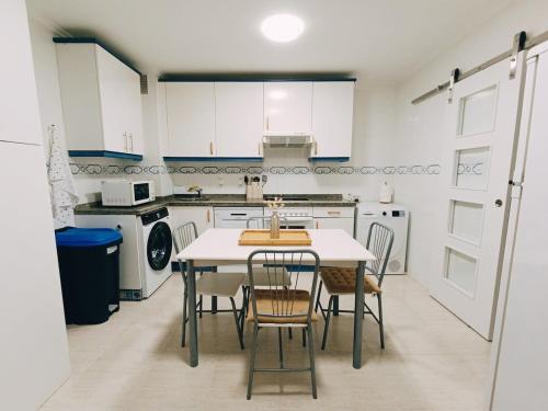 a kitchen with white cabinets and a table and chairs at El Llambrion in Posada de Llanes