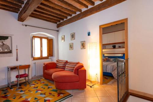 a living room with a red chair and a bed at La Casetta Nei Borghi Volterrani in Volterra