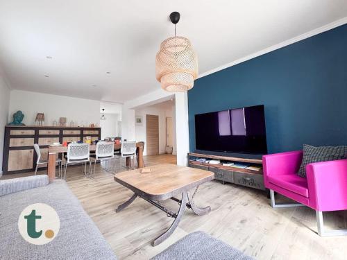 un salon avec une télévision, une table et des chaises dans l'établissement Tranquiloue - Maison Cosy à 15min du PuyduFou, aux Herbiers