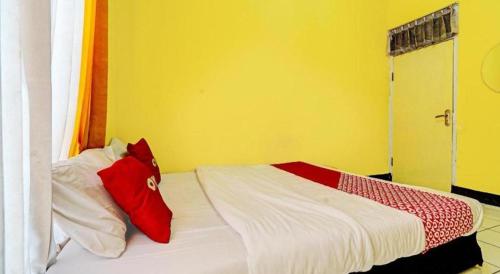 a bedroom with a bed with red and white pillows at Hotel O P3 Guest House in Bandung