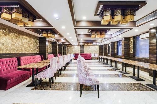 a row of tables and pink chairs in a restaurant at Palette Alandur Near Chennai Airport in Chennai