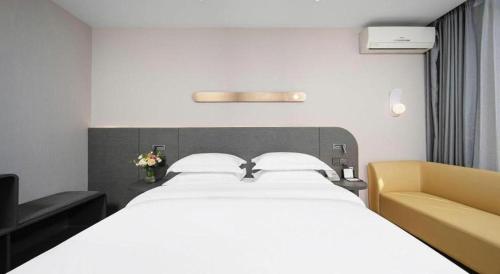 a bedroom with a large white bed and a yellow chair at Jinjiang Inn Changchun Xi An Avenue Branch in Changchun