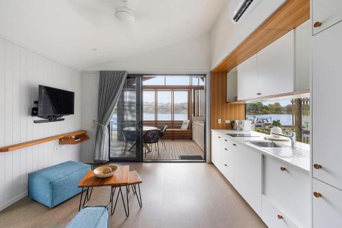 a kitchen and living room with white cabinets and a table at Reflections Evans Head - Holiday Park in Evans Head