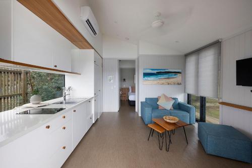 a living room with a blue chair and a kitchen at Reflections Evans Head - Holiday Park in Evans Head