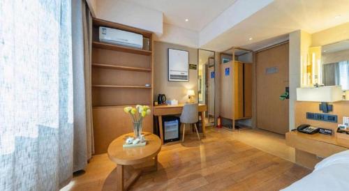 a hotel room with a bedroom with a desk and a table at V8 Ziyuangang Hotel in Guangzhou