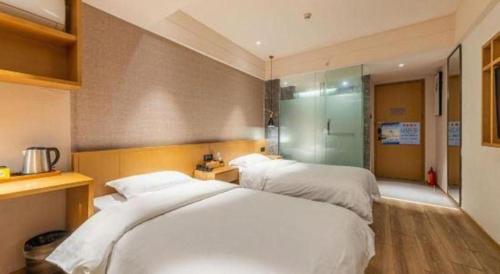 a bedroom with two white beds and a shower at V8 Ziyuangang Hotel in Guangzhou