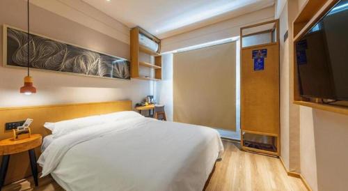 a bedroom with a white bed and a flat screen tv at V8 Ziyuangang Hotel in Guangzhou