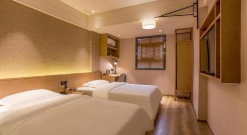 a hotel room with two beds and a television at V8 Ziyuangang Hotel in Guangzhou