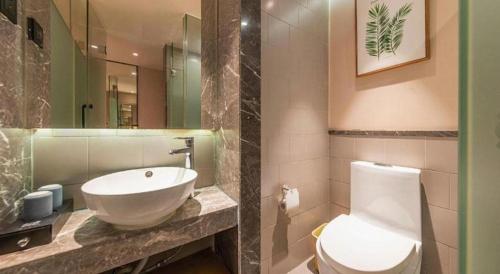 a bathroom with a white toilet and a sink at V8 Ziyuangang Hotel in Guangzhou