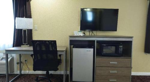 a room with a desk with a microwave and a tv at Best Western Hanford Inn in Hanford