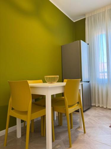 a dining room with a white table and yellow chairs at HOUSE on sunday SOLE in Crotone