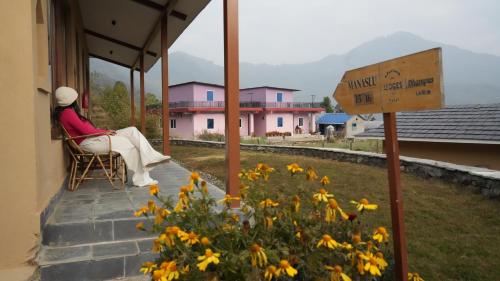 a woman sitting in a chair on the porch of a house at Mountain Lodges of Nepal - Dhampus in Kāskī