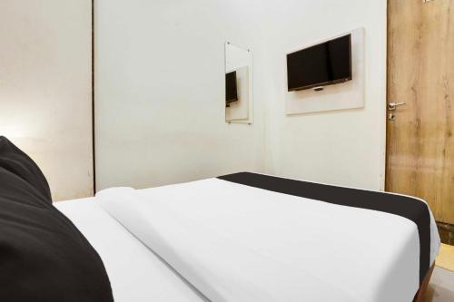 a bedroom with a white bed and a tv on the wall at Townhouse Ville Parle in Mumbai