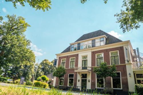 a large brick house with a black roof at Boetiek Hotel BonAparte Lochem in Barchem