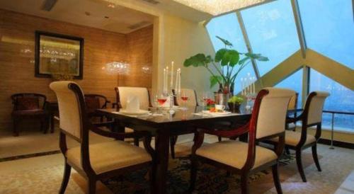a dining room with a table and chairs and a large window at New Century Grand Hotel Zhuji Yaojiang in Shaoxing