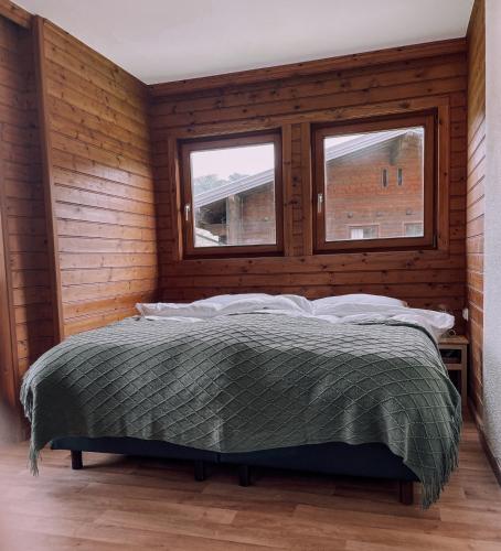 a bed in a wooden room with two windows at Das Luis in Altenmarkt im Pongau