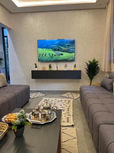 un soggiorno con un divano e una TV a parete di Beldi Chic à Sidi Ifni Confort Premium a Sidi Ifni