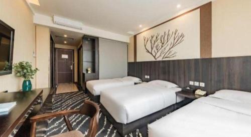 a hotel room with two beds and a desk at Kunming Long Way Hotel in Kunming