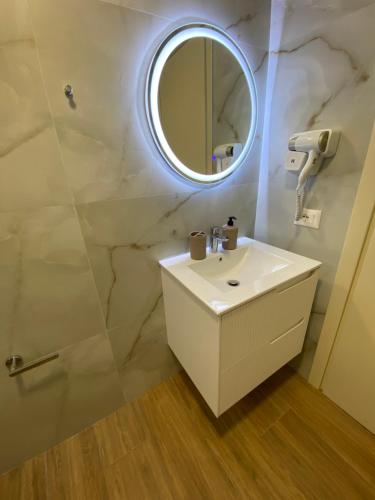 ein Badezimmer mit einem weißen Waschbecken und einem Spiegel in der Unterkunft Hajdini Apartament & Studios in Sarandë