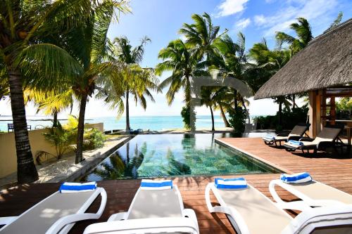 a resort pool with chairs and the ocean in the background at Villa Emerald in Post of Flacq