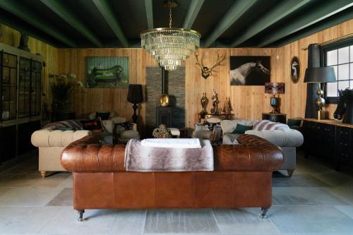 a living room with a leather couch and a chandelier at Domaine du Turbais in Luynes