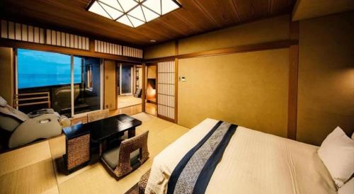 a bedroom with a bed and a desk and a window at Luxury Wa Hotel Kaze No Kaori in Ito