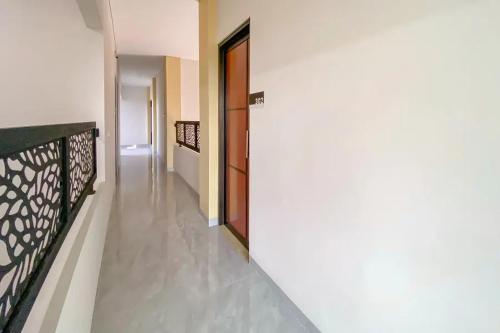 a hallway with a white wall and a door at Sans Stay Syariah Asyifa Purwokerto in Purwokerto