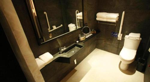 a bathroom with a sink and a toilet and a mirror at Noble Park Hotel in Hong Kong