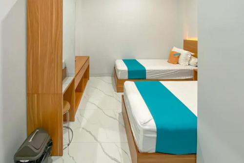 a room with two beds and a tv in it at Sans Stay Syariah Asyifa Purwokerto in Purwokerto