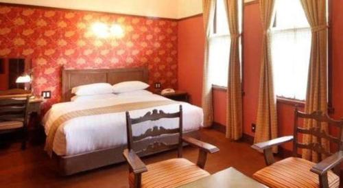 a bedroom with a large bed with red walls at Unzen Kanko Hotel in Unzen
