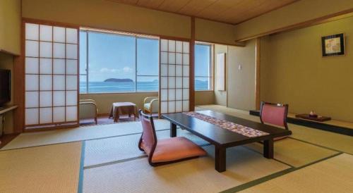a room with a table and chairs and windows at Hotel Shofuen in Toyohashi