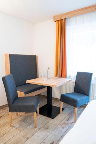 a table with two chairs and a table with glasses on it at Hotel Alpina in Kleinarl