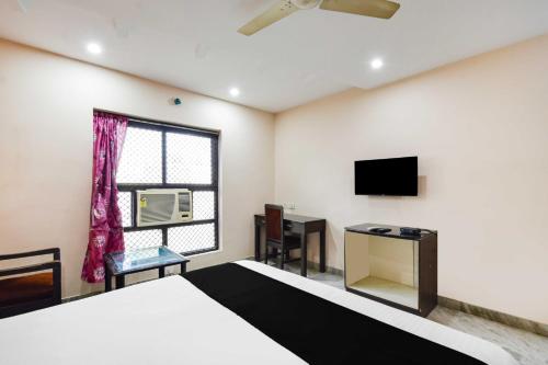 a bedroom with a bed and a tv and a window at Townhouse Secunderabad Near Railway Station Formerly Hotel Brahma in Hyderabad