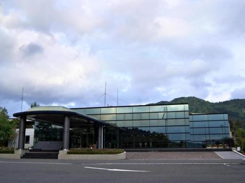 a building with a glass facade with a parking lot at Kyoto Keburikawa Hotel in Kameoka
