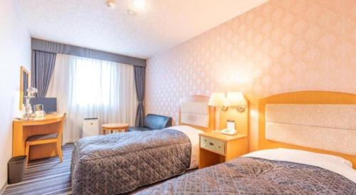 a hotel room with two beds and a desk at Tabist Sunshine Koga in Koga