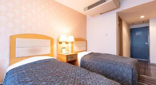 a hotel room with two beds and a window at Tabist Sunshine Koga in Koga