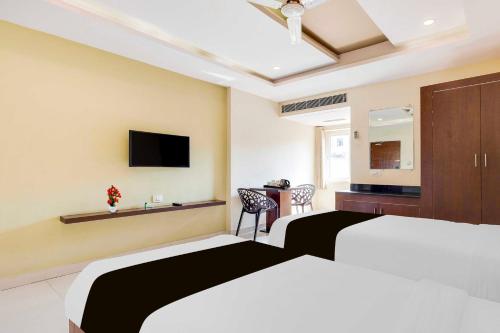 a hotel room with two beds and a television at Collection O Dwarka Nagar Ramatalkies in Visakhapatnam