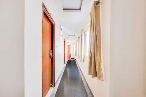 a hallway with white walls and a black floor and a door at Collection O Dwarka Nagar Ramatalkies in Visakhapatnam